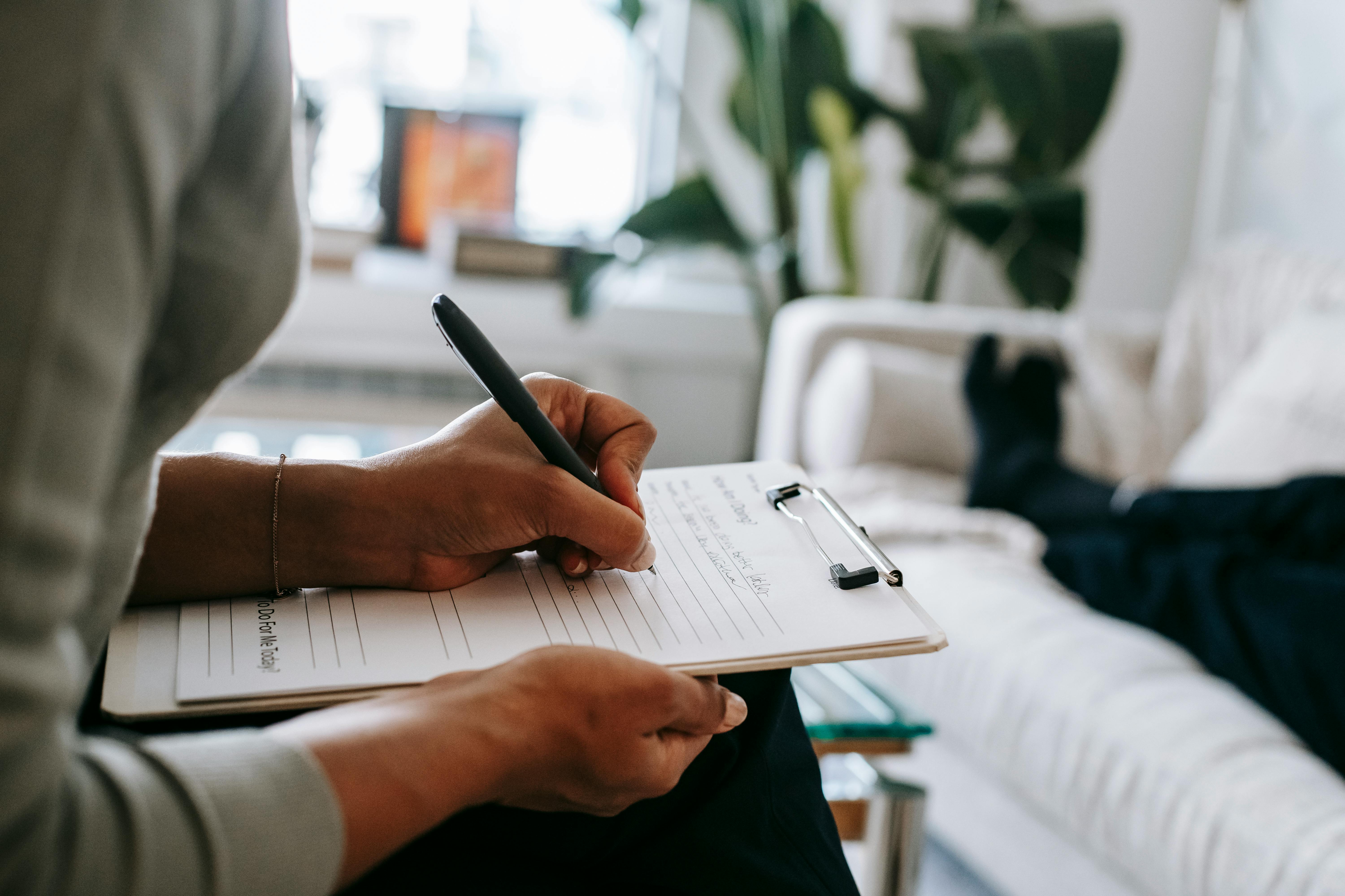 Photo of a persons' hand filling out a paper on a clipboard